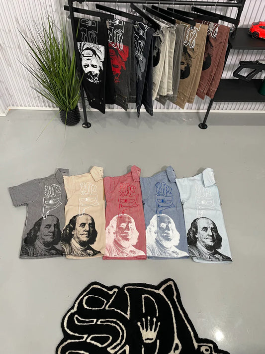 Collection of graphic t-shirts on a rack with a plant and black bag in the background.