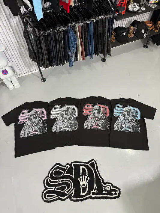 Black t-shirts with graphic designs on a white floor, with 'SDL' logo in front.